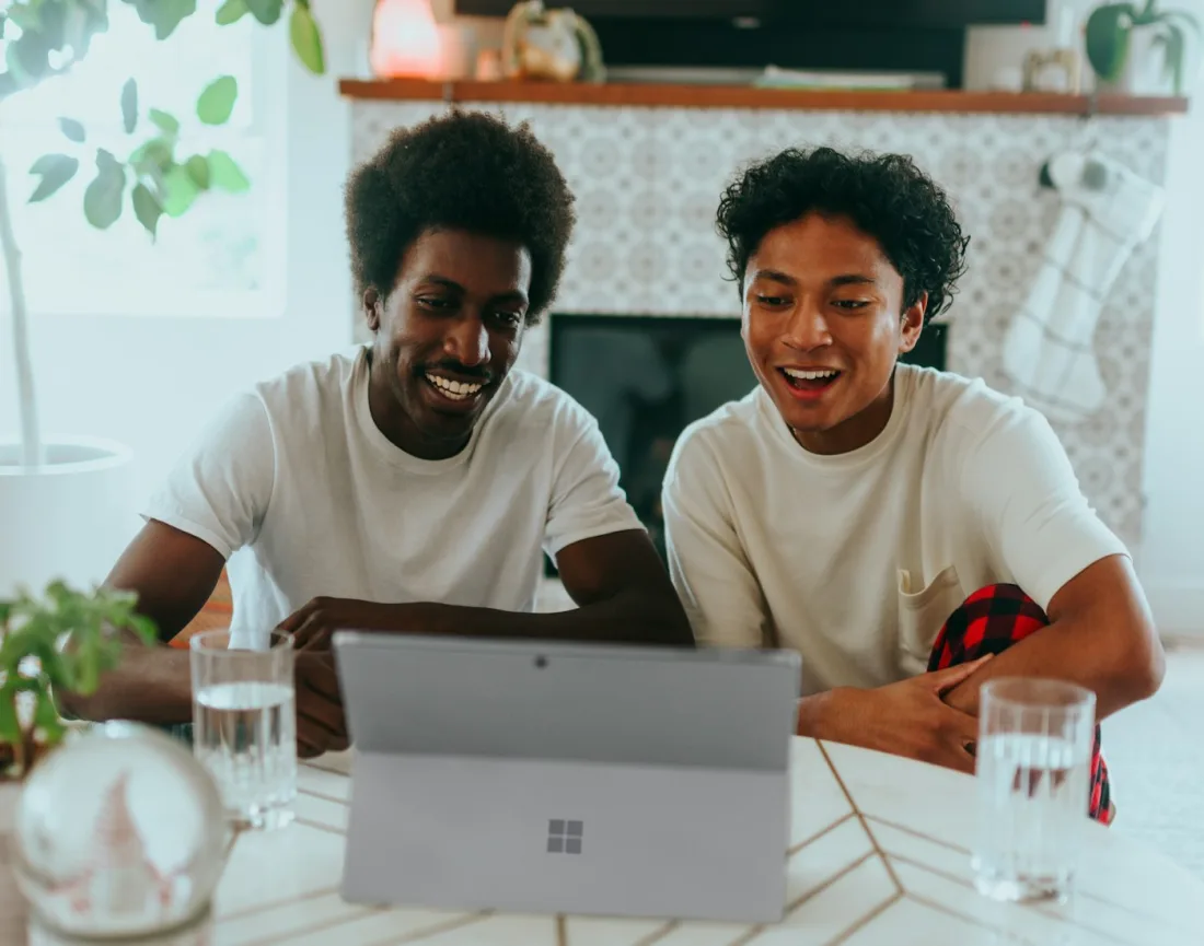 Two friends lighting up at a laptop as the answer they needed comes back